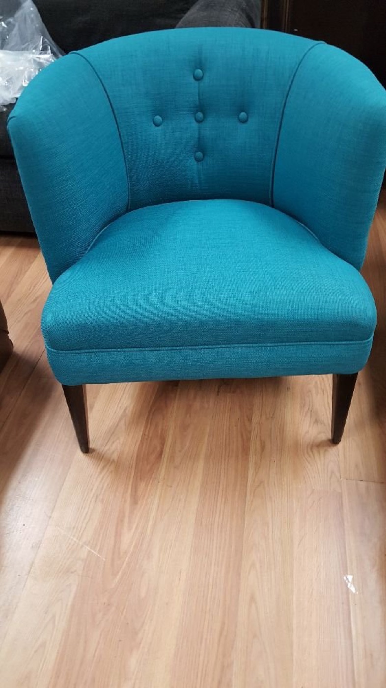 A small armchair in bright teal with tapered wooden legs.