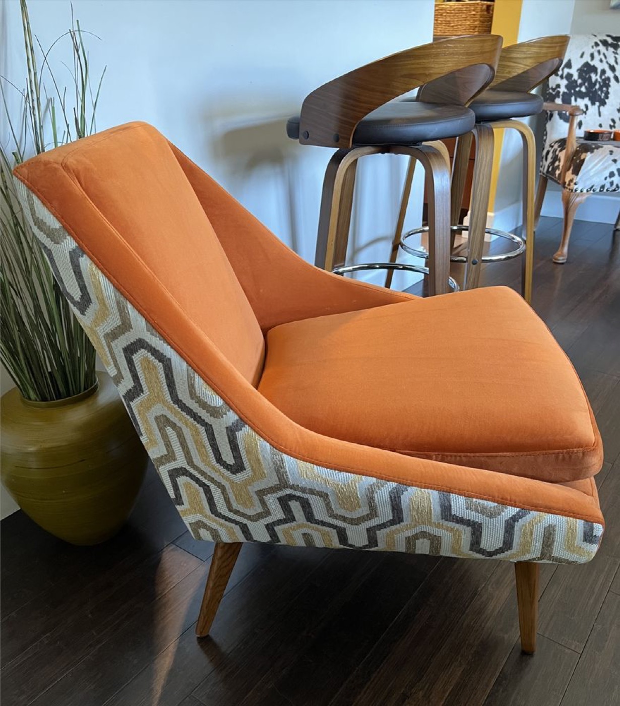 A mid-century armchair in orange with a patterned back panel.